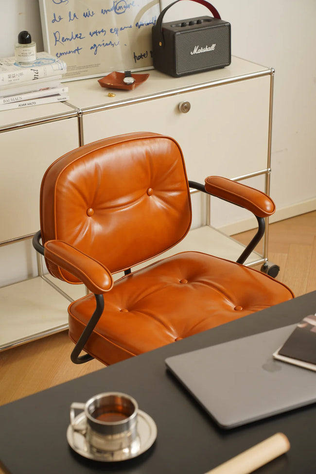 Brown leather office computer arm chair in a home office setting with a desk and Marshall speaker.