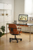 Modern office desk with a computer and swivel arm chair in a well-lit room.