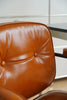 Close-up of a brown office leather swivel arm chair with a blurred background