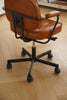 Brown office swivel chair with black metal frame on a wooden floor