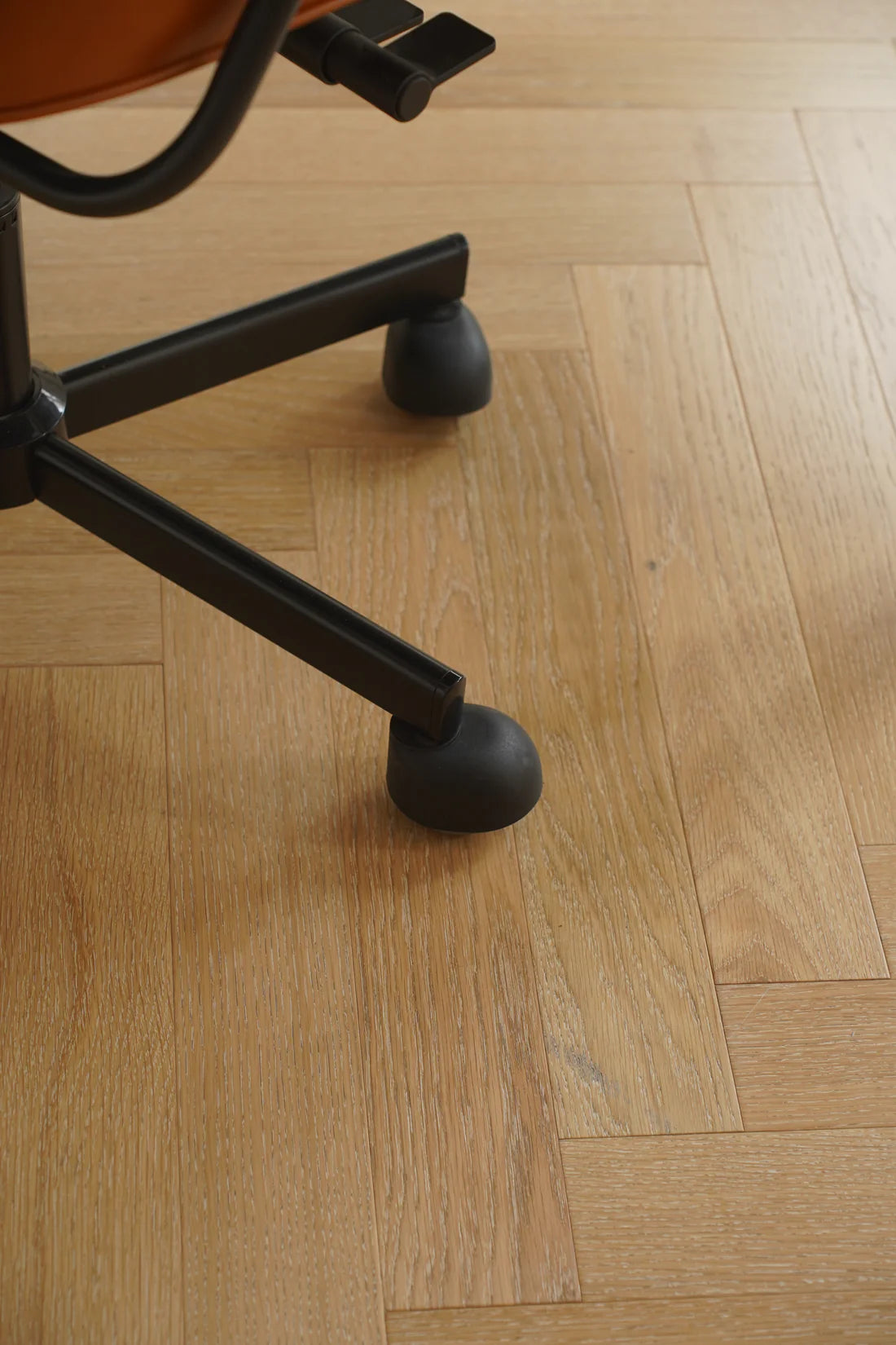 Close-up of a swivel chair wheel on a wooden floor