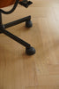 Close-up of a swivel chair wheel on a wooden floor