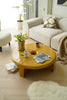 Living room with a yellow round coffee table, white sofa, and decorative items.