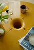 Yellow small storage round coffee table with a cup, flowers, and magazine on top