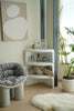 Modern interior with a white chair, small coffee table with storage, and plants.