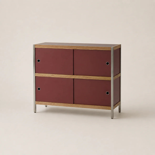 Small cabinet with maroon doors and wooden accents on a beige background