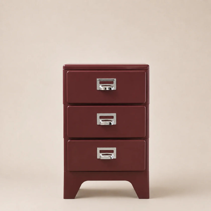 Red metal file cabinet with three drawers on a beige background
