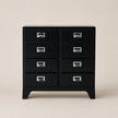Black dresser with multiple drawers on a beige background