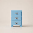 Light blue three-drawer cabinet with silver handles on a beige background