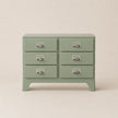 Green dresser with six drawers on a beige background