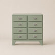 Green dresser with multiple drawers on a beige background