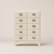 White dresser with multiple drawers on a beige background