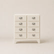 White dresser with multiple drawers on a plain background