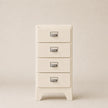 White four-drawer cabinet with silver handles on a beige background