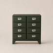 Green metal cabinet with multiple drawers on a beige background