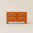 Orange dresser with four drawers on a beige background