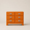 Orange dresser with silver handles on a beige background