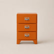 Orange three-drawer filing cabinet with metal handles on a beige background