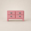 Pink dresser with four drawers on a beige background