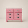 Pink dresser with six drawers on a beige background