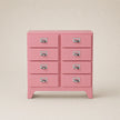 Pink dresser with multiple drawers on a beige background