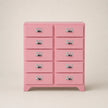 Pink dresser with multiple drawers on a beige background