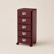 Maroon metal file cabinet with four drawers on a beige background