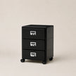 Black three-drawer filing cabinet on wheels with silver handles against a beige background