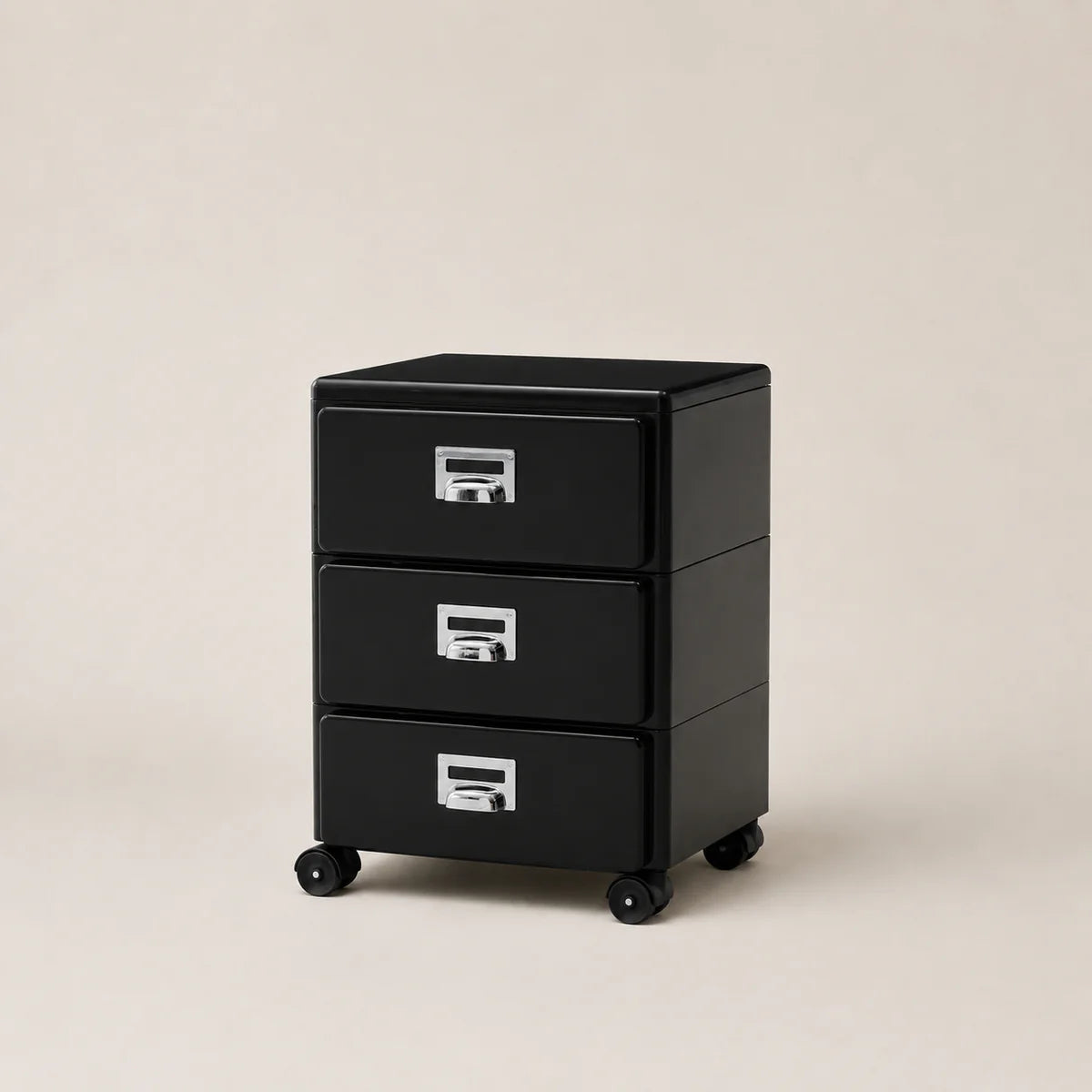 Black three-drawer filing cabinet on wheels with silver handles against a beige background
