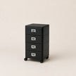 Black metal file cabinet with four drawers on a beige background