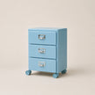 Light blue three-drawer filing cabinet on wheels with silver handles against a beige background