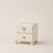 Cream-colored two-drawer nightstand with wheels on a beige background