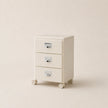 Beige three-drawer filing cabinet on wheels with metallic handles against a beige background