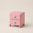 Pink jewelry box with two drawers on wheels against a beige background