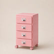 Pink three-drawer filing cabinet on wheels with silver handles against a beige background