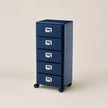 Blue metal storage cabinet with four drawers on wheels against a beige background