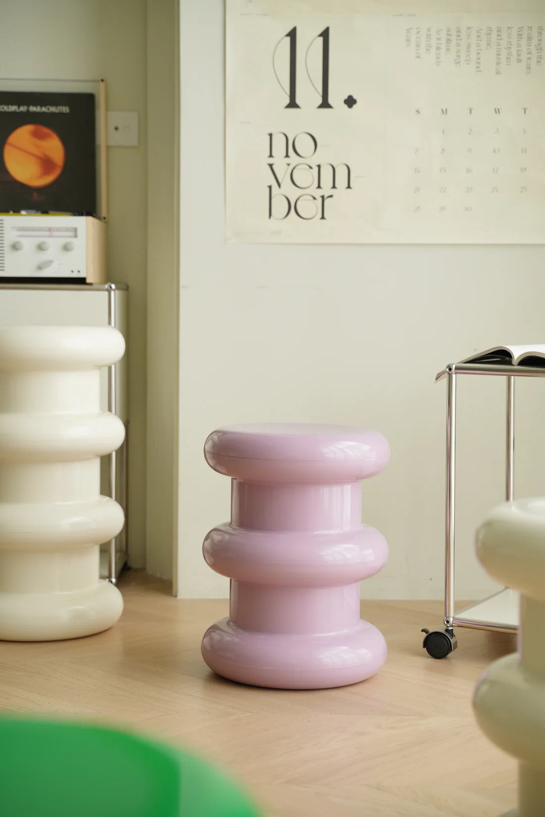 Pink and white cylindrical plastic step stools in a room with a calendar on the wall.