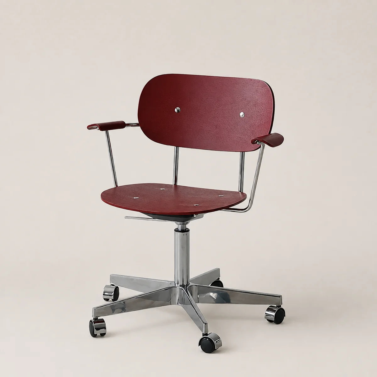 A modern office chair with a dark red seat and backrest, supported by a chrome metal base with five casters, set against a plain light beige background.