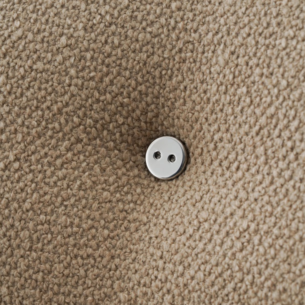 Close-up of a textured beige fabric surface with a small round white button centered on it.
