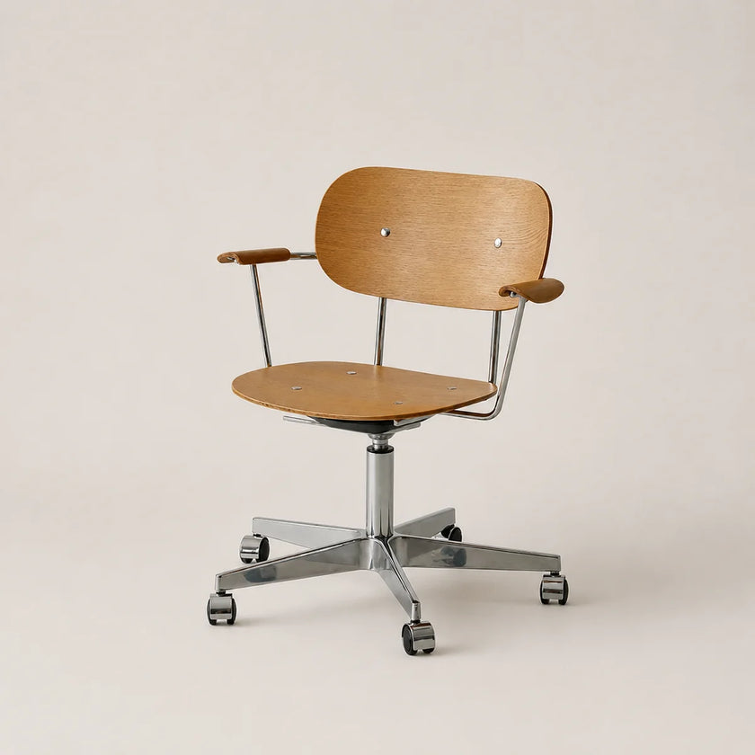 A modern office chair with a light oak wood seat and backrest, supported by a chrome five-star base with casters, photographed against a solid light beige background.