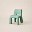 Green children's chair on a beige background