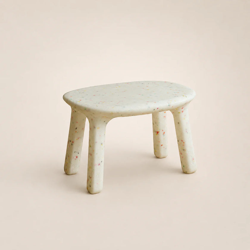 Small round table with a textured surface on a plain background