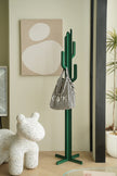 Green cactus-shaped coat rack stand with a striped bag against a light wall with abstract art.