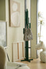 Green modern coat rack with a striped bag against a wall with abstract art