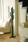 Green cactus-shaped coat rack stand with a bag on it in a living room setting.