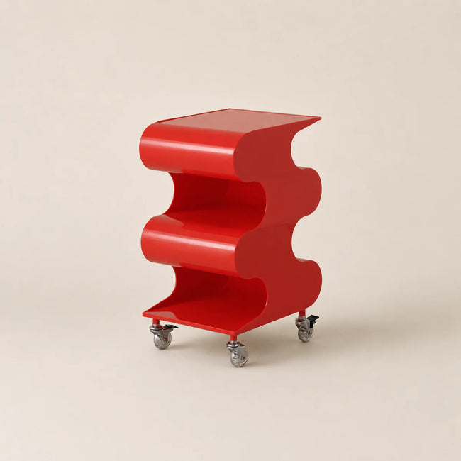 Red, wavy-shaped side table on wheels against a beige background