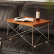Small wooden sofa side table with an open book and a bottle on a dark leather sofa.