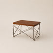 Small wooden table with metal legs on a beige background
