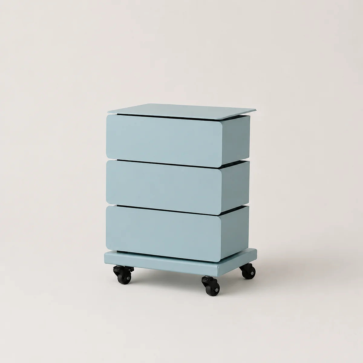 A three-drawer rolling nightstand in a light pastel blue color, featuring a flat top surface and black caster wheels, photographed against a neutral off-white background.