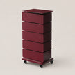 A tall, five-drawer rolling storage cabinet in a deep burgundy finish, featuring a flat top and black caster wheels, set against a solid light beige background.